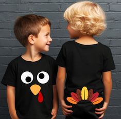 two young boys wearing matching thanksgiving shirts with turkey faces on the front and back of their shirts