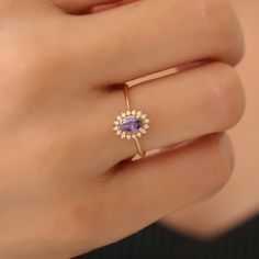 a woman's hand wearing a ring with an amethorate and diamond center