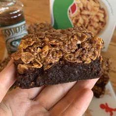 a person holding up a chocolate cookie with nuts on top