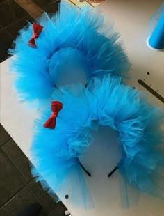 two blue tulle wreaths with red bows are on top of a piece of paper