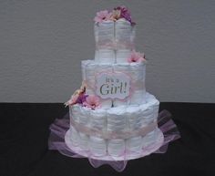 a three tiered diaper cake with pink flowers on top