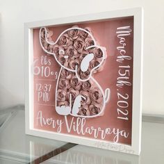 a pink and white framed sign with flowers in the shape of an elephant on it