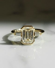 an emerald cut diamond ring with three baguets on the band and side stones