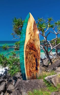 a surfboard sitting on top of a rock near the ocean