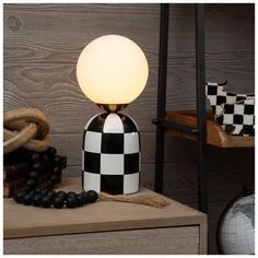 a black and white lamp sitting on top of a wooden table next to a basket