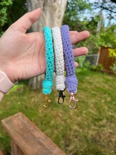 a person holding three different colored bracelets in their hand with trees in the background