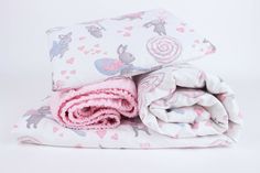 two blankets folded on top of each other with pink and blue designs in the background