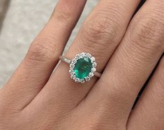 a close up of a person's hand with a green ring on their finger