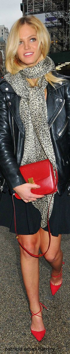 a woman in black and white dress holding a red purse