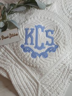 a close up of a quilt with the kc's logo on it and flowers