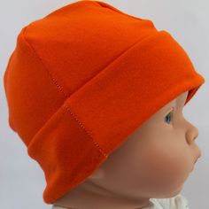 an orange hat is shown on top of a doll's head and it has blue eyes