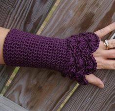 a woman's hand wearing purple knitted arm warmers and holding a cell phone