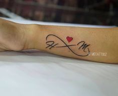 a person with a tattoo on their arm that has a heart and an m in the middle