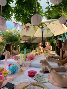 a group of women sitting at a table with plates and cups on it, all wearing party hats