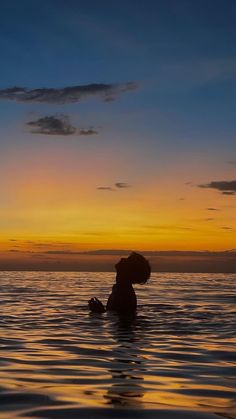 a person in the water at sunset with their back turned to the camera and head tilted