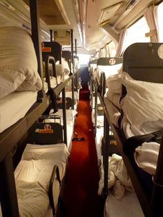 bunk beds are lined up in a room with white sheets and pillows on the floor