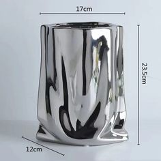 a silver vase with black lines on the side and measurements for each one in front