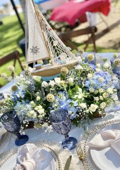 a table set with plates, silverware and a sailboat decoration on top of it