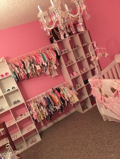 a baby's room with pink walls and white shelves, chandelier and crib