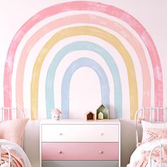 a child's bedroom decorated in pastel colors with a rainbow painted on the wall