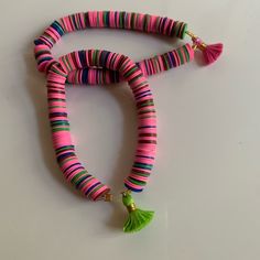 a pink, green and blue beaded necklace with tassels on the end