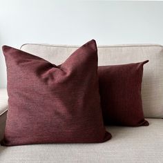 two red pillows sitting on top of a white couch