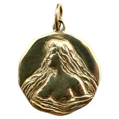 The image on this 14k gold medallion was originally taken from an Art Nouveau locket. Kirsten’s Corner created a mold using the face of the locket, and then hand-carved details to emphasize and add depth to the original design. The maiden is surrounded by long flowing hair that morphs into the water that surrounds her. She wears the water wrapped around her almost like a negligee, revealing her bare breasts in the seductive, graceful image. The nine-sided medallion has soft angles and could be engraved on the back. Part of Kirsten’s Corner Signature Collection. Since each piece is individually carved it is a one-of-a-kind Art Nouveau inspired contemporary piece. The medallion weighs 6.1 grams. It has a 7/8” diameter, with an oval bail that is 5 x 7.3 mm. Art Nouveau Locket, Flowing Hair, Gold Medallion, Art Nouveau Jewelry, La Face, Signature Collection, Locket, Original Design, The Face