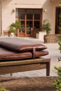 a large brown leather pillow sitting on top of a wooden bench next to a building