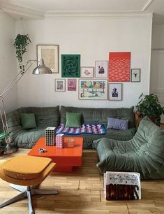 a living room with green couches and pictures on the wall above them in various colors