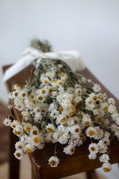 a bunch of white flowers tied to a wooden table with a white bow on it