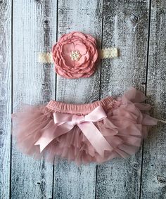 two pieces of pink tutule and headband on wooden planks with the word,