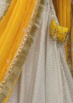 Haldi yellow lehenga with mirror work. The blouse is made of rawsilk with flutter sleeves in chiffon and all over mirror work. Skirt is made of brocade and has wide mirror work borders. Chiffon dupatta with sequins and mirror work. The dress will be made to order in your size. I'll send you a measurement sheet once you order for the measurements. Dress can be created in any color as the fabric is custom dyed. Please convo me if you have any questions or need any customisation. White And Yellow Lehenga For Haldi, White Sharara With Cutdana For Diwali, White Cutdana Sharara For Navratri, White Sharara With Cutdana For Navratri, Festive White Cutdana Sharara, Eid Anarkali Pre-draped Saree With Gota Work, White Chanderi Sharara With Traditional Drape, Navratri Dola Silk Sharara With Mirror Work, White Sharara With Cutdana In Traditional Drape