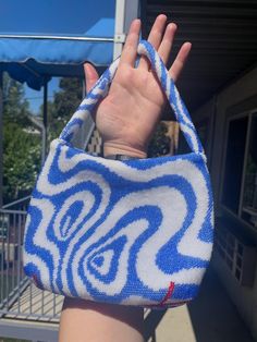 a hand holding onto a blue and white purse