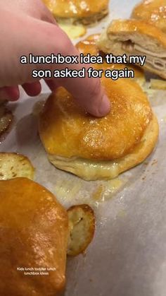 a person is picking up some food from a tray with other pastries on it