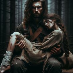 a man with long hair holding a woman in his arms while sitting on the ground