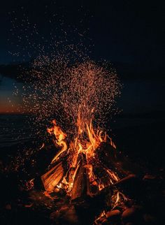 a bonfire with lots of fire and water in the background