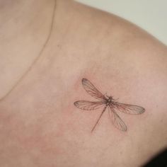 a small dragonfly tattoo on the chest