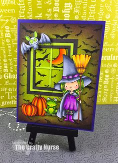 a handmade halloween card with a little witch holding a broom and pumpkins in front of a window