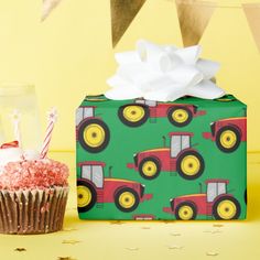 a cupcake next to a wrapping box with a tractor design on it and a candle