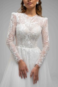 a woman in a white wedding dress with long sleeves and sheer lace on the top