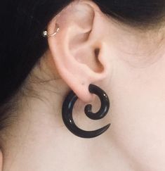 a close up of a person's ear with an earring in the shape of a spiral