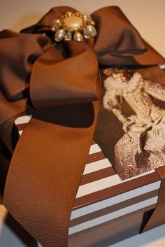 a gift wrapped in brown ribbon with an ornament on top