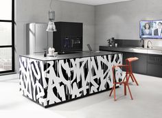 a black and white kitchen with two stools in front of the counter top, television on