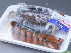 there are two cooked lobsters on the plastic plate and one is covered in ice