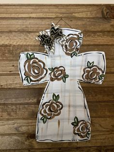 a cross made out of fabric with flowers on the front and sides, hanging on a wooden wall