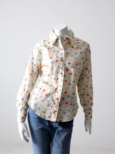 "This is a vintage floral shirt by Sears Mates from Junior Bazaar. The floral shirt features blue and red flowers. The shirt is 50% cotton and 50% polyester. CONDITION In good condition with wear consistent with age and use. Small stain spots front bust and lapel. APPROXIMATE FIT: M MEASUREMENTS Bust: 40\" .. 101.6 cm Length: 24.5\" .. 62.2 cm Shoulders: 15.5\" .. 39.7 cm Sleeve: 23\" .. 58.42 cm 72216" Classic Collared Tops With Floral Print, Classic Collared Top With Floral Print, Collared Cotton Blouse With Floral Print, Classic Floral Print Button-up Shirt, Classic Button-up Shirt With Floral Print, Classic Floral Print Button-up Top, Classic Floral Print Spring Tops, Classic Floral Print Tops For Spring, Classic Floral Print Tops For Daywear