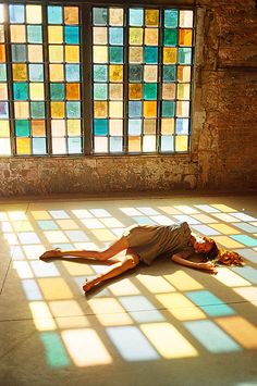 a man laying on the ground in front of a window with stained glass behind him