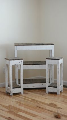 three white wooden tables sitting on top of a hard wood floor next to a wall