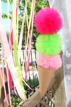 an ice cream cone with pink, green and yellow pom - poms hanging from it