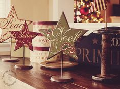 three wooden stars sitting on top of a table next to each other in front of a christmas tree